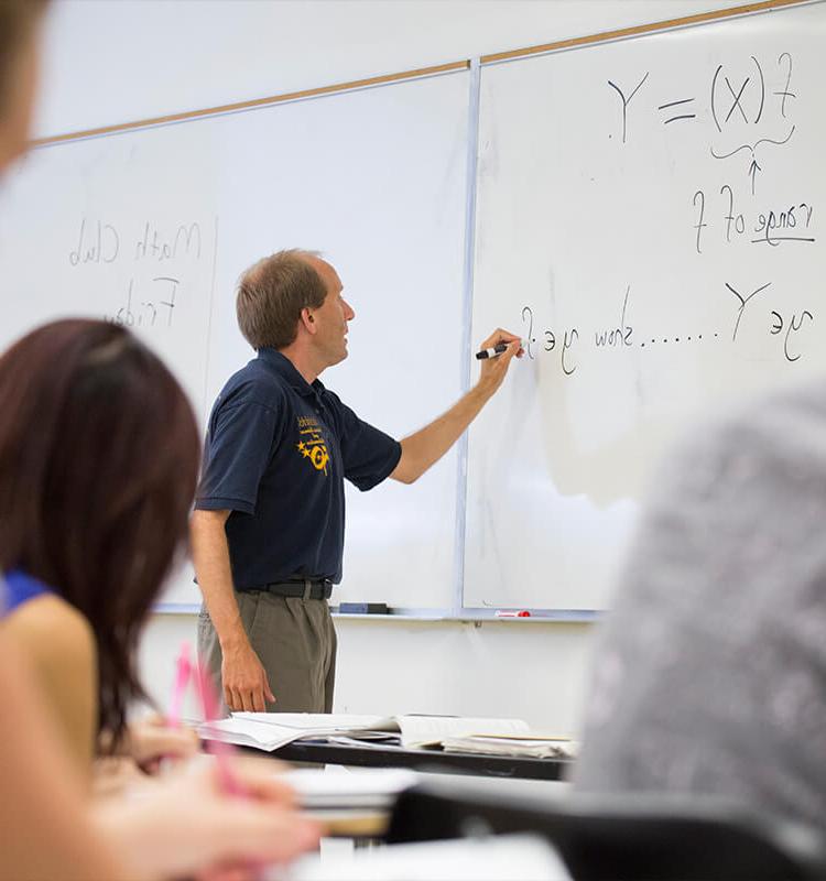 Professor writes math equation on white board